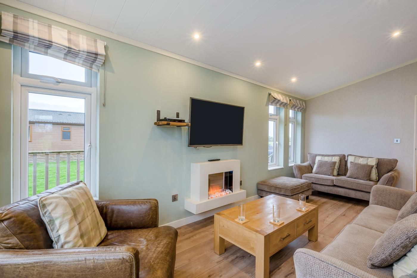 Una sala de estar con chimenea, televisor montado encima y un conjunto de sofás.