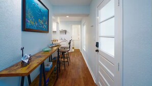 A hallway with a wooden table, chairs, a framed picture, and a door.