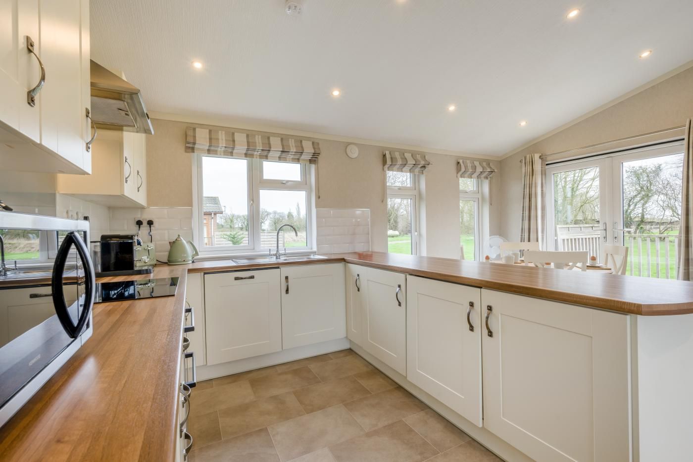 A kitchen with white cabinets, a wooden countertop, and a view of the outdoors.