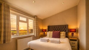A bedroom with a large bed, two bedside tables with lamps, a window with curtains, and a radiator. - 1 Bed in Athelington (oc-r35078) (Athelington)