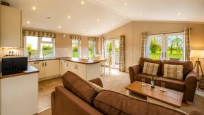 A spacious living area with a sofa, coffee table, and a kitchen area with a dining table. - 1 Bed in Athelington (oc-r35078) (Athelington)