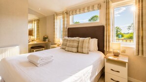 A hotel room with a large bed, bedside tables, a mirror, and a window with a view of greenery. - 2 Bed in Athelington (oc-v35079) (Athelington)