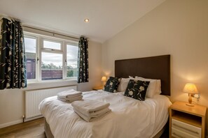 Een hotelkamer met een bed, twee bedlampen, een raam met gordijnen en uitzicht op het omliggende gebied.