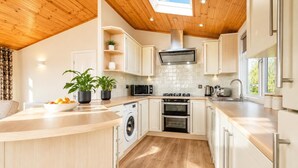 A modern kitchen with a wooden ceiling, built-in appliances, and a large window. - 2 Bed in Athelington (oc-h35081) (Athelington)