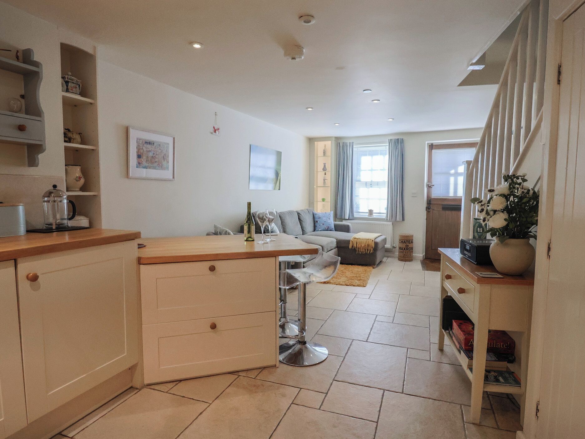 A modern kitchen with a central island, a dining area with a sofa, and a staircase leading to an upper level.