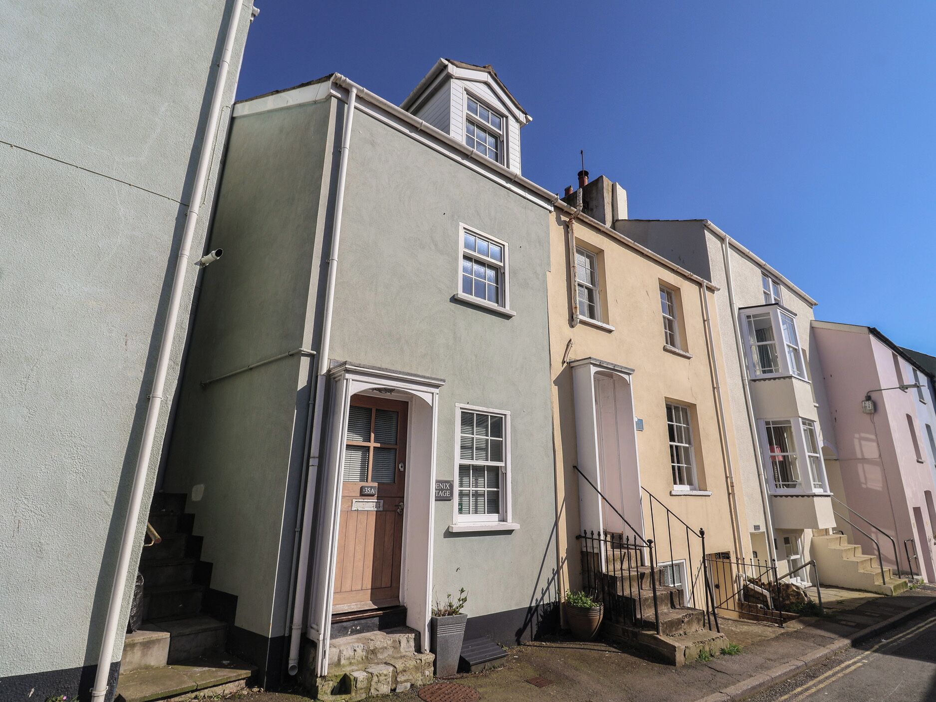 A row of townhouses with a central entrance, a small porch, and a staircase leading to the entrance.