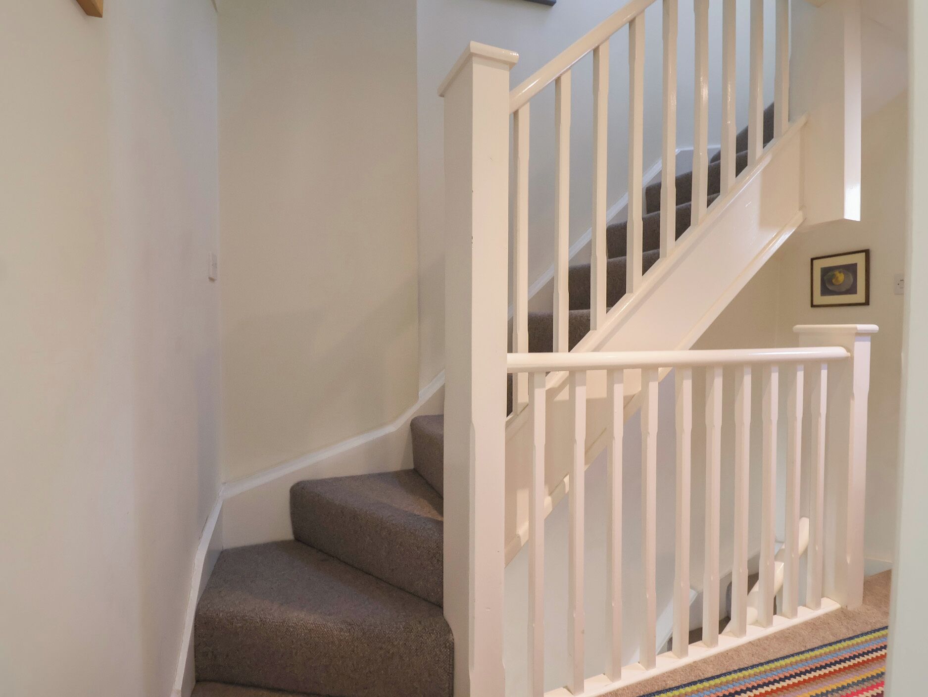 A staircase with white railings and carpeted steps.