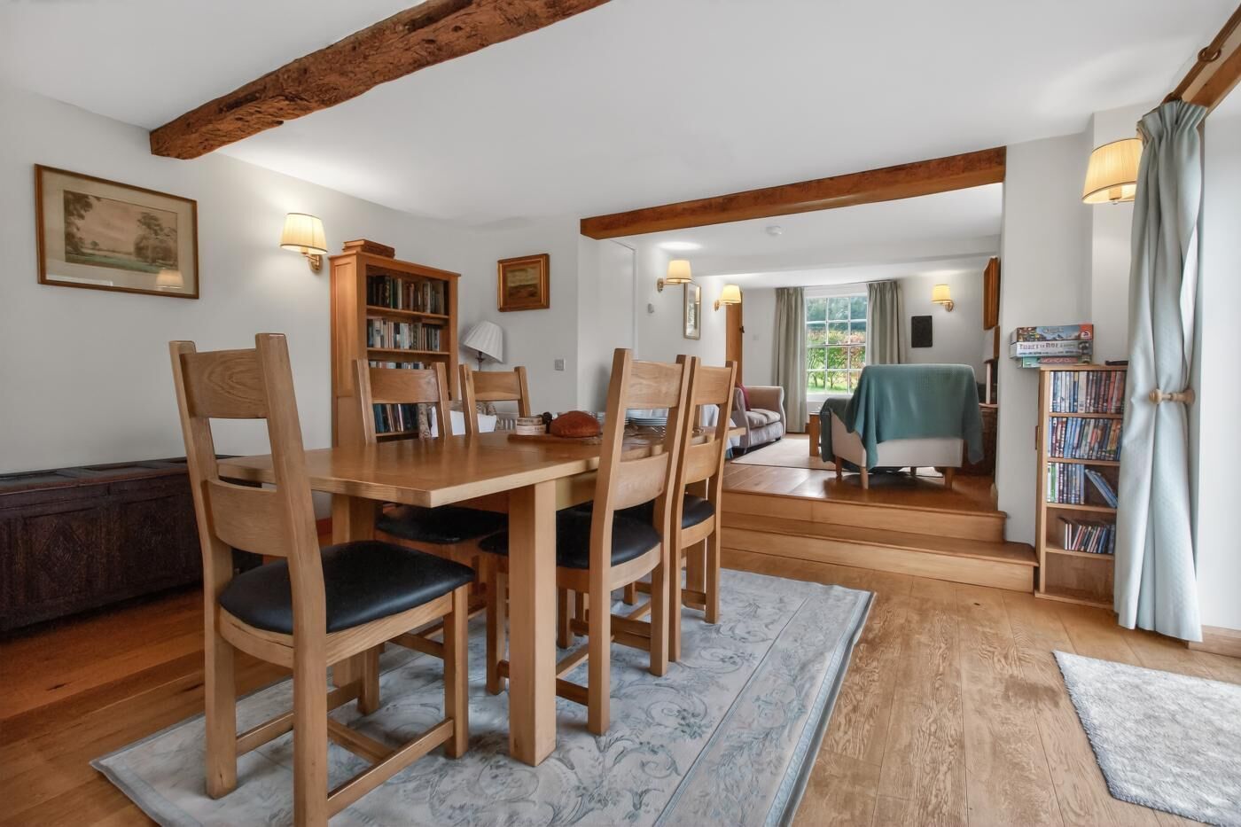 En matplats med ett träbord och stolar, en bokhylla och en soffa i bakgrunden.