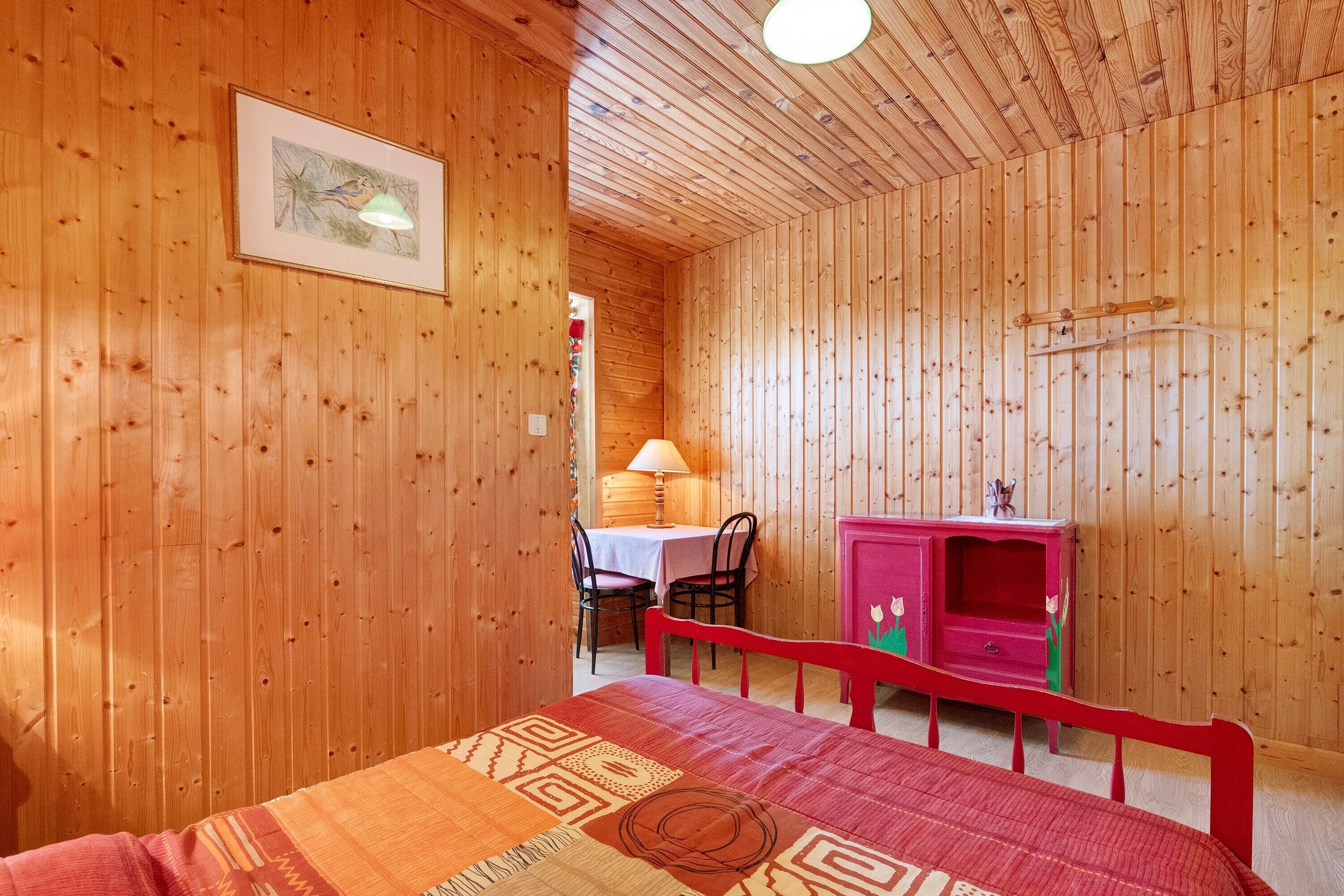 A wooden room with a bed, a desk, and a chair.