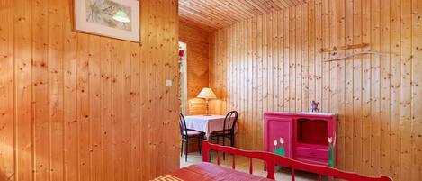A wooden room with a bed, a desk, and a chair.