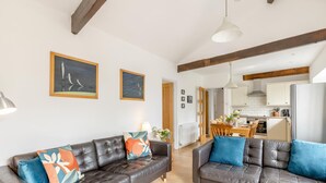 Uma sala de estar moderna com dois sofás de couro, uma área de jantar e uma cozinha visível através de uma porta aberta.