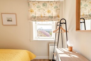 Ein Schlafzimmer mit einem Bett, einem Heizkörper, einem Fenster mit Blick, einem Hängekorbsessel und einem Holztisch.