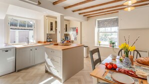 A modern kitchen with wooden beams, a dining area with a table set for two, and a view of the outdoors. - 2 Bed in Ampleforth (oc-c37505) (Ampleforth)