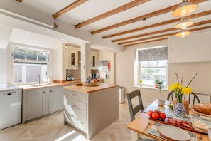 A modern kitchen with wooden beams, a dining area with a table set for two, and a view of the outdoors. - 2 Bed in Ampleforth (oc-c37505) (Ampleforth)