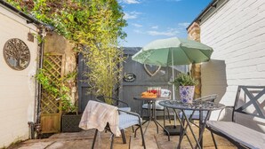A patio with a table and chairs, a potted plant, and a sign reading 'Cottage.' - 2 Bed in Ampleforth (oc-c37505) (Ampleforth)