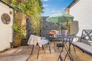 A patio with a table and chairs, a potted plant, and a sign reading 'Cottage.' - 2 Bed in Ampleforth (oc-c37505) (Ampleforth)