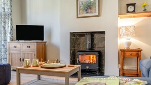 A living room with a fireplace, a television, a table with decorative items, and a magazine. - 2 Bed in Ampleforth (oc-c37505) (Ampleforth)