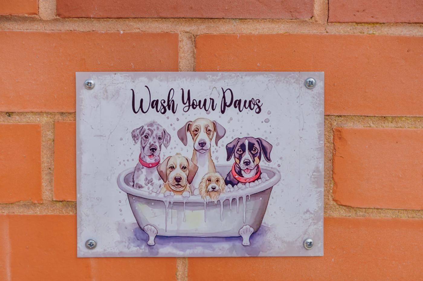 A sign with the text 'Wash Your Paws' and illustrations of dogs in a bathtub.