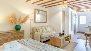 Un dormitorio acogedor con cama, sofá, cómoda de madera, espejo y lámpara.