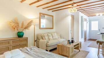 A cozy bedroom with a bed, a sofa, a wooden dresser, a mirror, and a lamp.