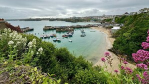 Un pueblo costero con barcos amarrados en un muelle, una playa de arena y abundante vegetación.