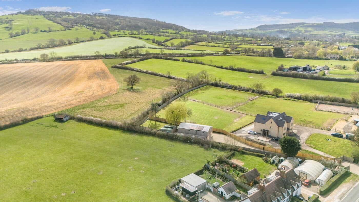 An aerial view of a rural landscape with fields, a farmhouse, and a small cluster of houses.