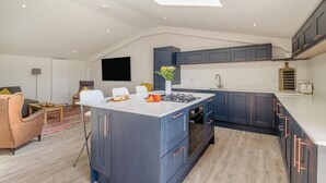 Une cuisine moderne dotée d’un îlot central, de meubles de couleur sombre et d’une verrière.