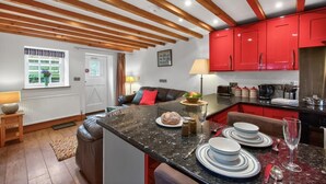 Une cuisine moderne avec des meubles rouges, un plan de travail en marbre et un coin repas comprenant un canapé et une table dressée pour le repas.
