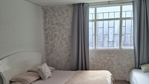 A bedroom with a bed, a nightstand, a dresser, and a window with curtains. - Comfortable 1-bedroom apartment #301 near the U.S. Embassy (Bogotá, D.C.)