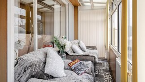 Une pièce avec un lit, une fenêtre, un vase de fleurs et un magazine posé sur le lit.
