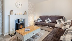 Un salon avec une cheminée, un canapé, une table basse et une horloge au mur.