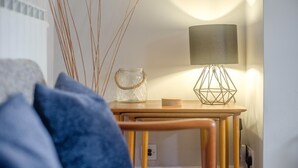 Een kamer met een houten tafel, een lamp en een glazen pot met een touw hengsel.