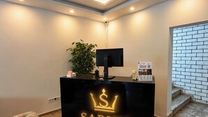 A reception desk with a black counter, a television, and a plant. - SARUM ÇEŞME (İzmir)