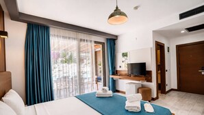 A hotel room with a bed, a TV, a desk, and a view of the outdoors. - SARUM ÇEŞME (İzmir)