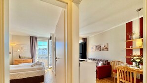 Habitación de hotel con cama, escritorio, silla, televisión y vistas al exterior.