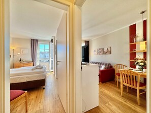 Ein Hotelzimmer mit Bett, Schreibtisch, Stuhl, Fernseher und Blick ins Freie.