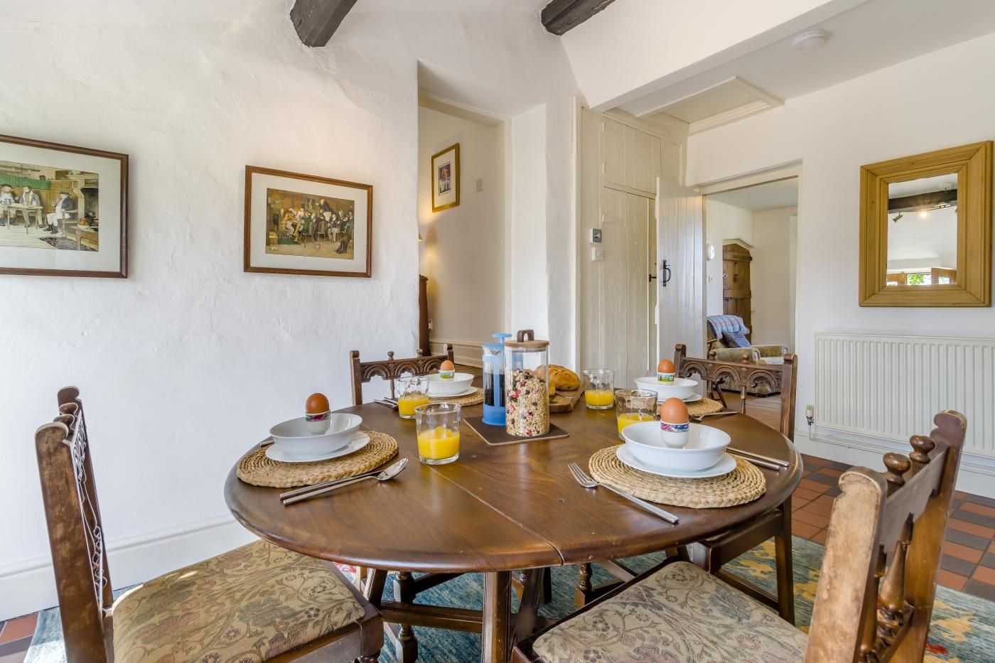 Un coin repas avec une table ronde en bois, des chaises et des aliments pour le petit-déjeuner.