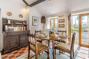 A dining area with a wooden table, chairs, a buffet, and a view through a glass door. - 2 Bed in Hay-on-wye (oc-bn226) (Clifford)