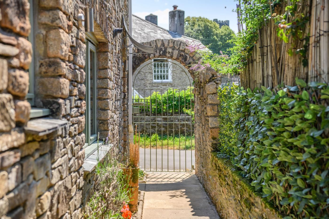 A stone building with a narrow entrance, a metal gate, and a clear view of the surrounding greenery.