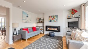 A modern living room with a fireplace, a sofa, a television, and a bookshelf. - 3 Bed in Plymouth (oc-49520) (Newton Ferrers)