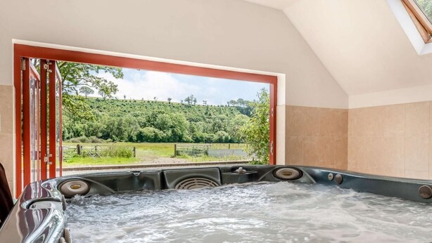 Ein Whirlpool mit Blick auf eine grüne Landschaft durch ein Fenster.