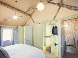 Un dormitorio con una cama grande, un armario y una estantería con ropa.