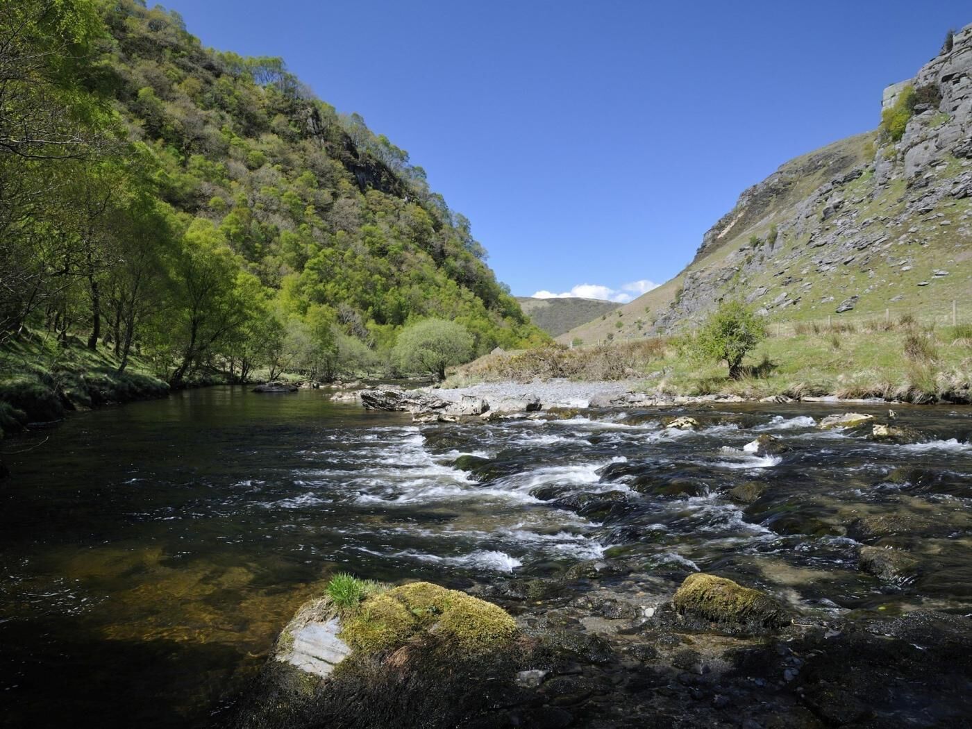 A river flowing through a valley with rocky terrain and dense greenery.