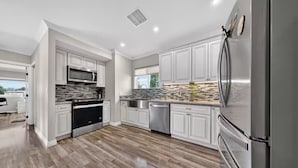A modern kitchen with stainless steel appliances, white cabinetry, and a herringbone wood floor. - Peaceful Tujunga Retreat Mountain Views Near Universal (Los Angeles)