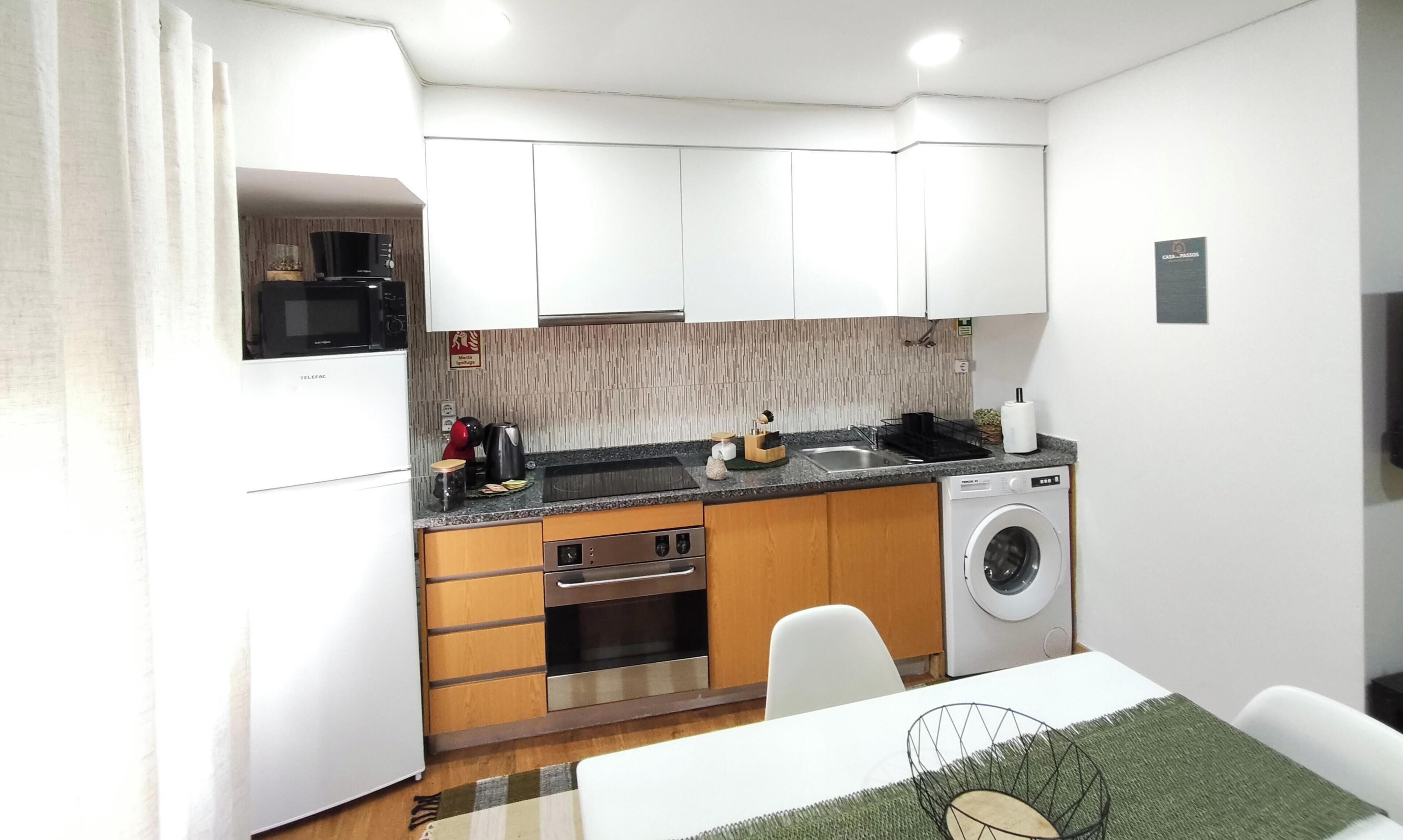 Cocina compacta con microondas, cafetera y lavadora.