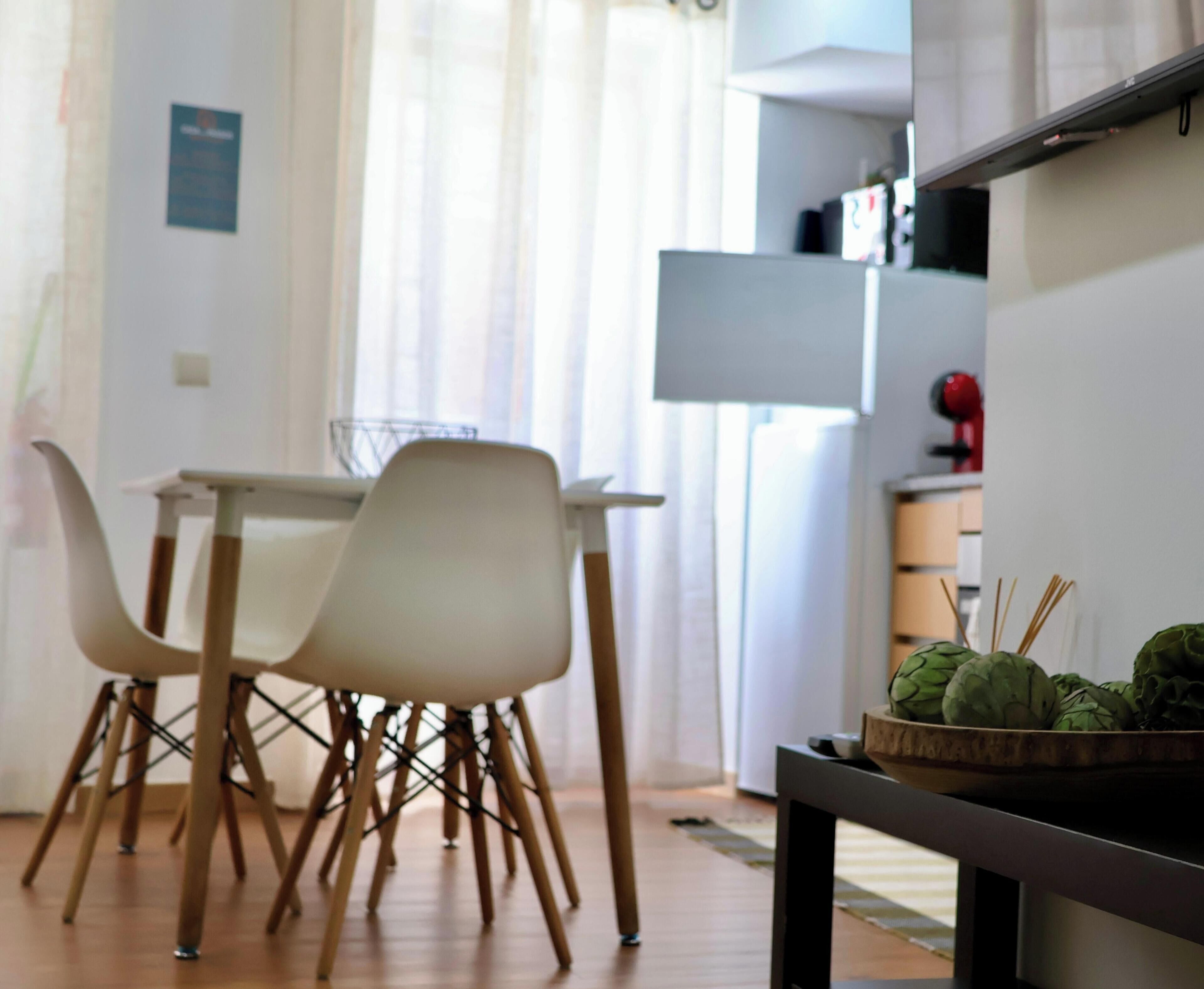 Une cuisine moderne avec une table et des chaises, un réfrigérateur et un panier d’artichauts.