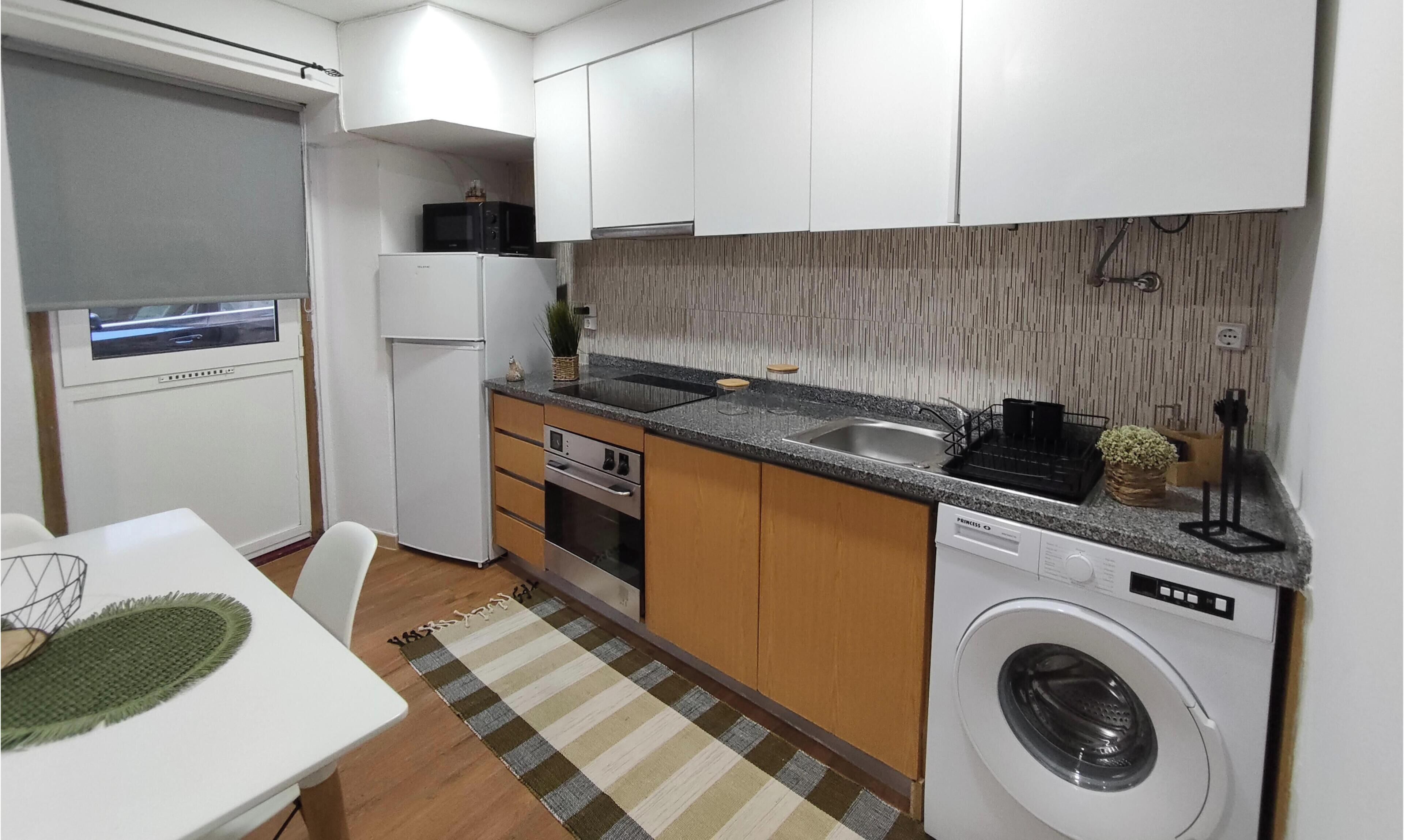 Une cuisine compacte équipée d’un lave-linge, d’un four à micro-ondes et d’un lave-vaisselle.