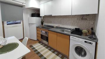 Cocina compacta con lavadora integrada, microondas y lavavajillas.