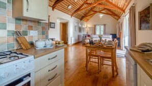 Uma cozinha com fogão a gás, armários de madeira e uma área de jantar com mesa e cadeiras.
