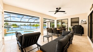 Amplo espaço interno com vista para a piscina, ventilador de teto e churrasqueira.